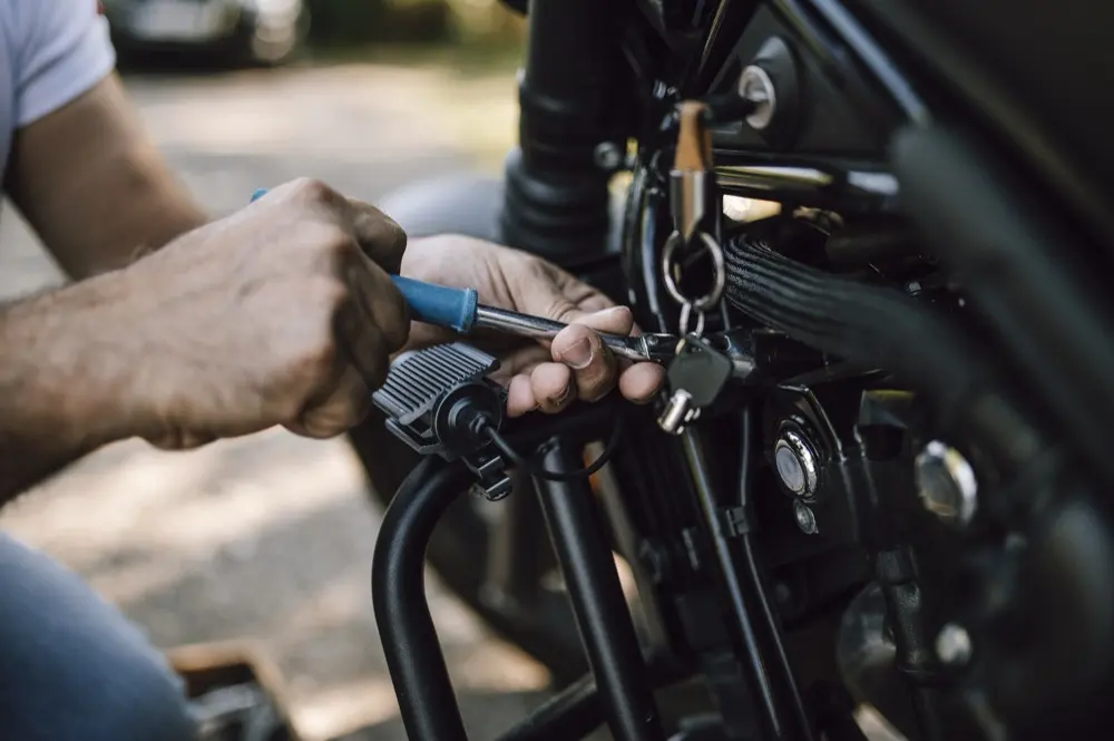 Mechaniker zieht mit dem Ratschenschlüssel eine Schraube am Motorrad fest